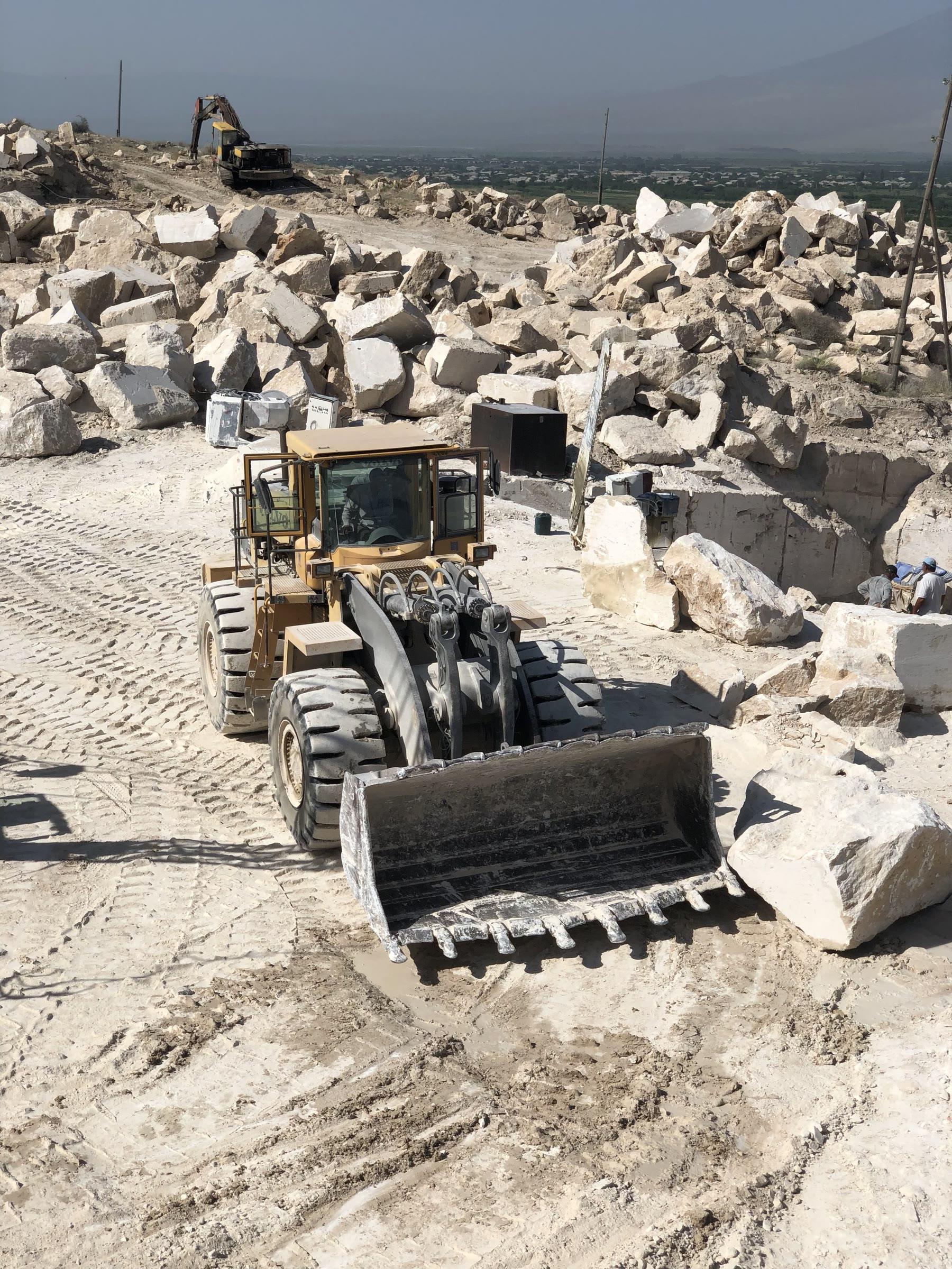 Wheel loader moving travertine blocks across the quarry yard