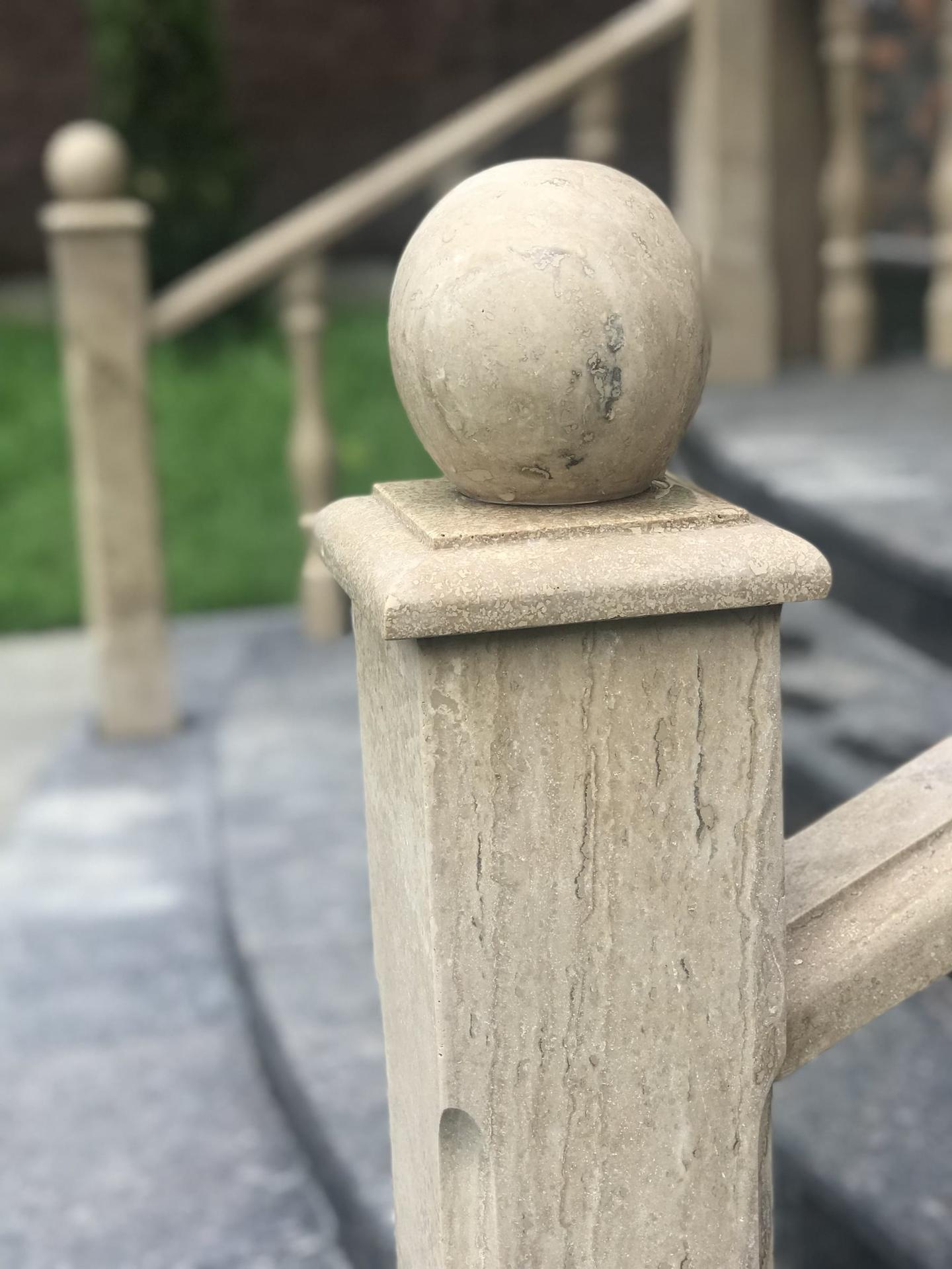 Travertine newel post with a ball finial on an outdoor stair