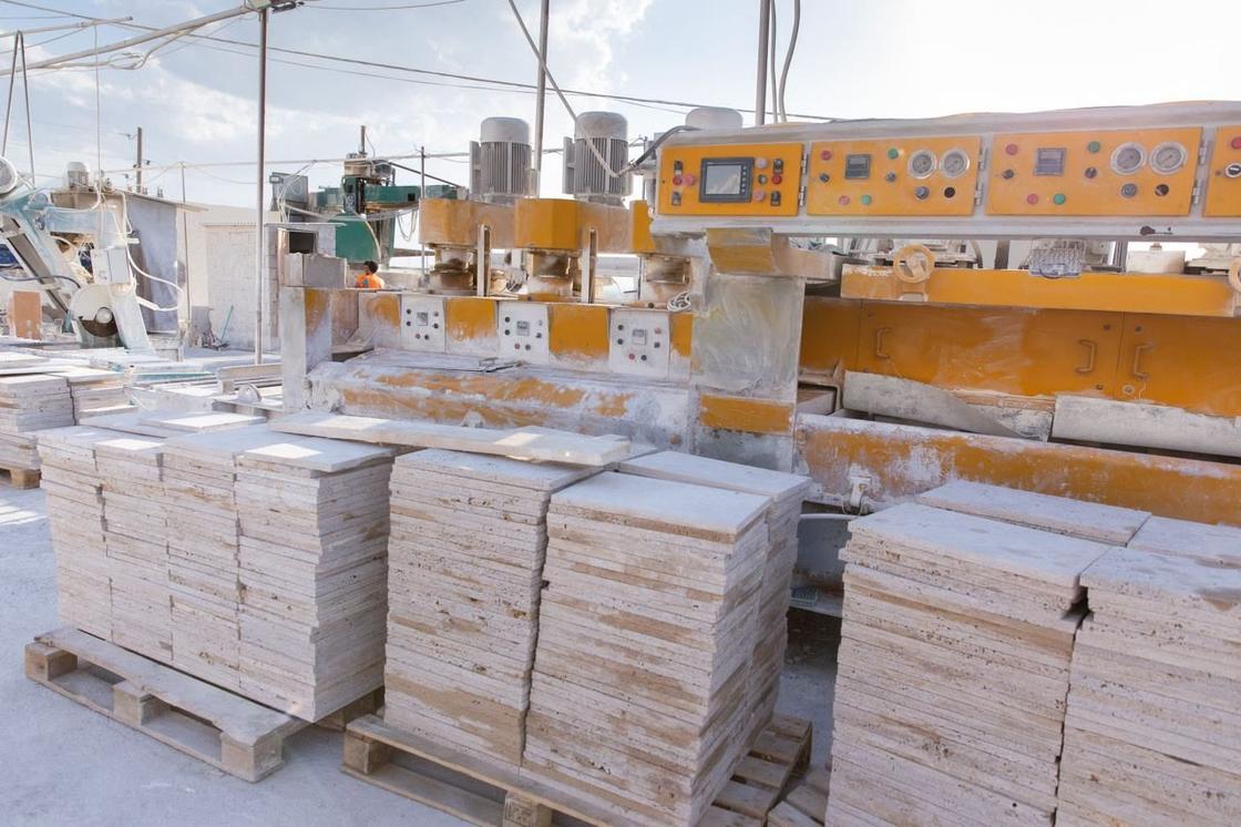 Travertine tiles stacked on pallets beside the finishing line